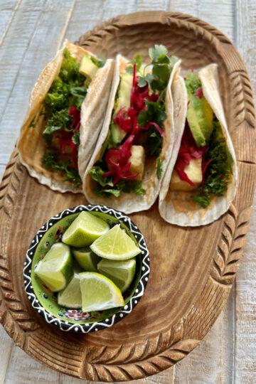 Vegan Fusion tacos in wooden bowl, plated with lime wedges