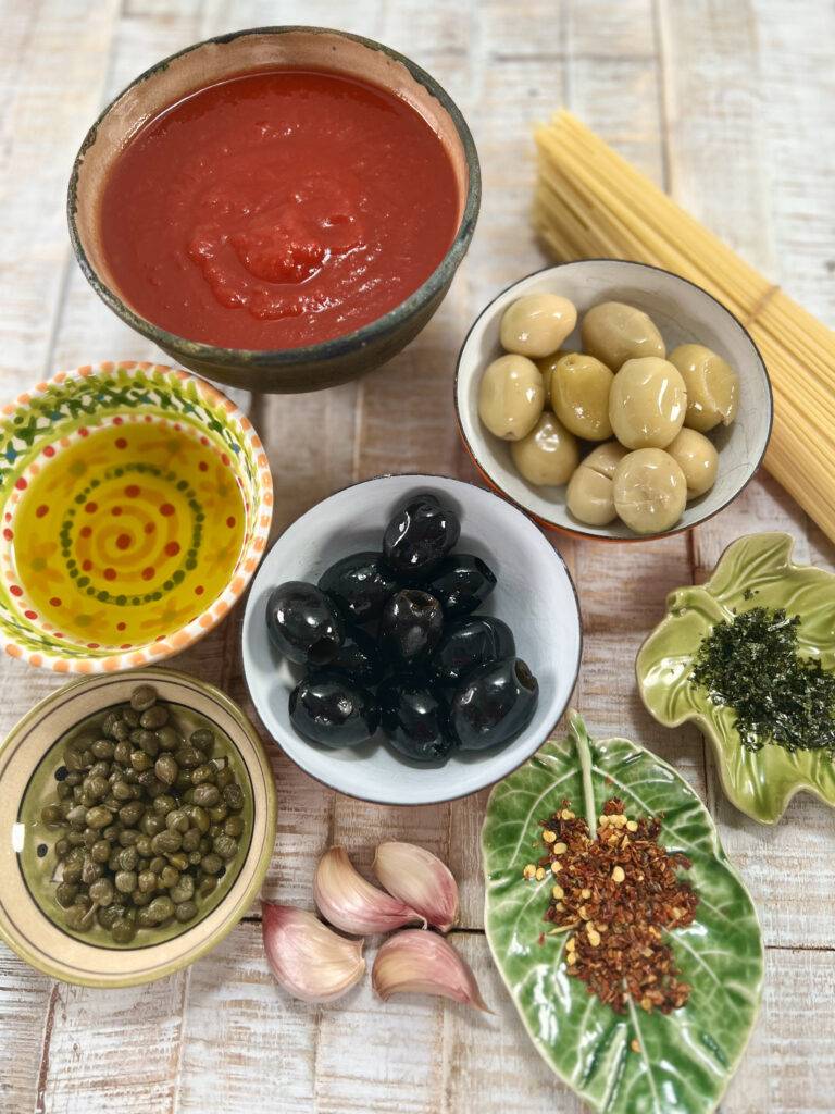 Ingredients for Spaghetti alla Puttanesca, presented in colourful bowls