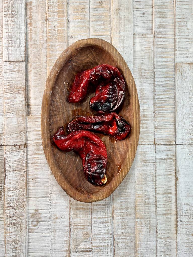 Three roasted pepper in wooden bowl