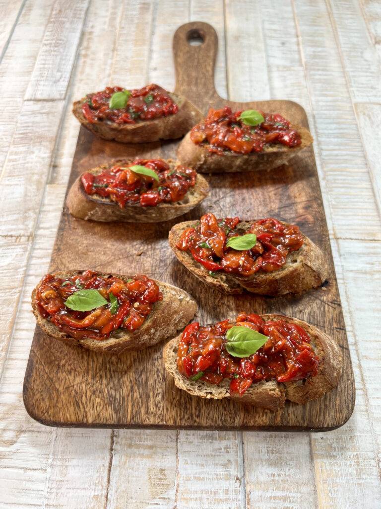 A second angle of the sweet pepper crostini presented on a wooden board.