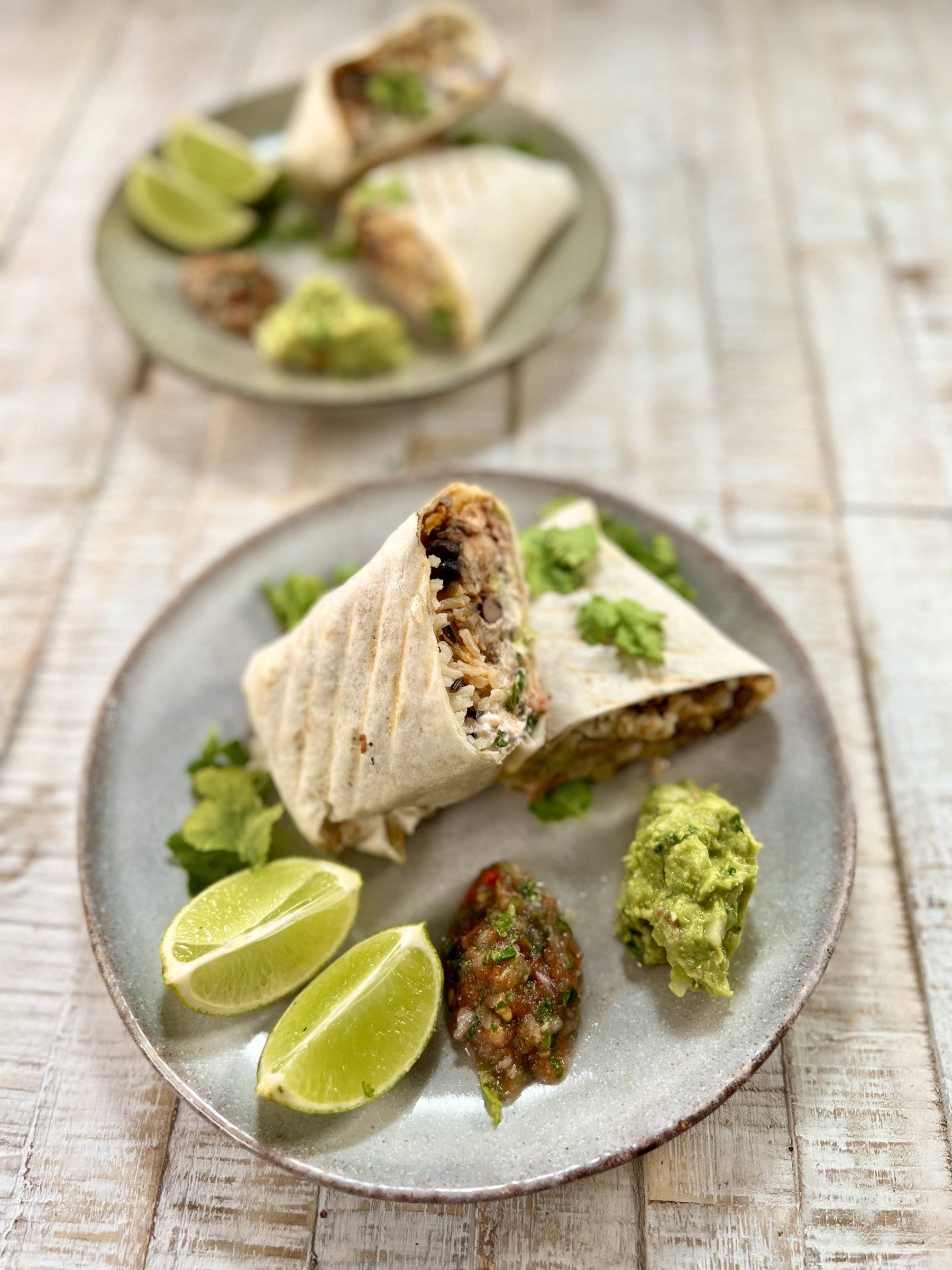 Delicious jackfruit burrito served, plated with salsa, guacamole, lime and cilantro