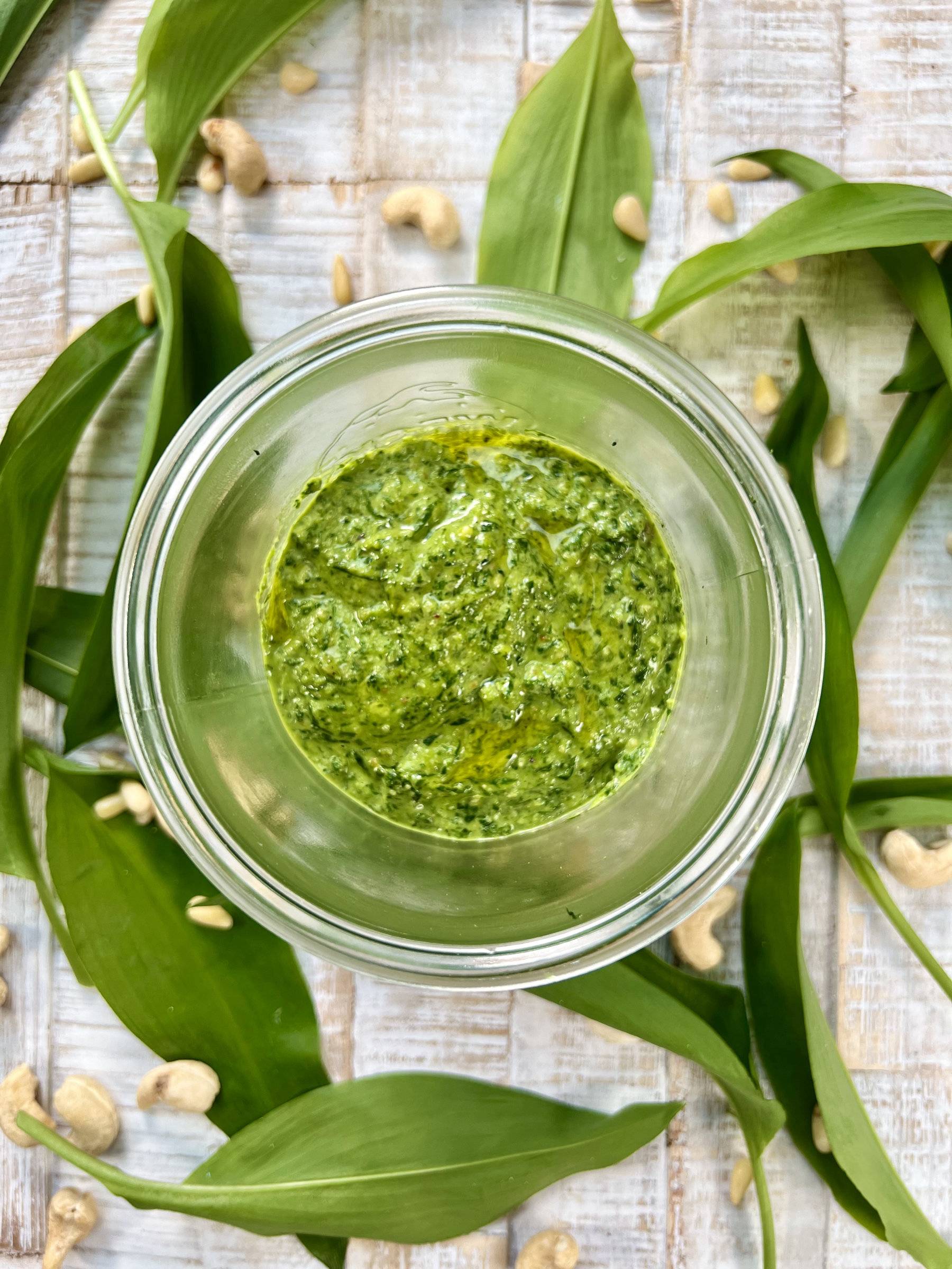Wild garlic pesto in jar, decorated with toasted nuts and wild garlic leaves