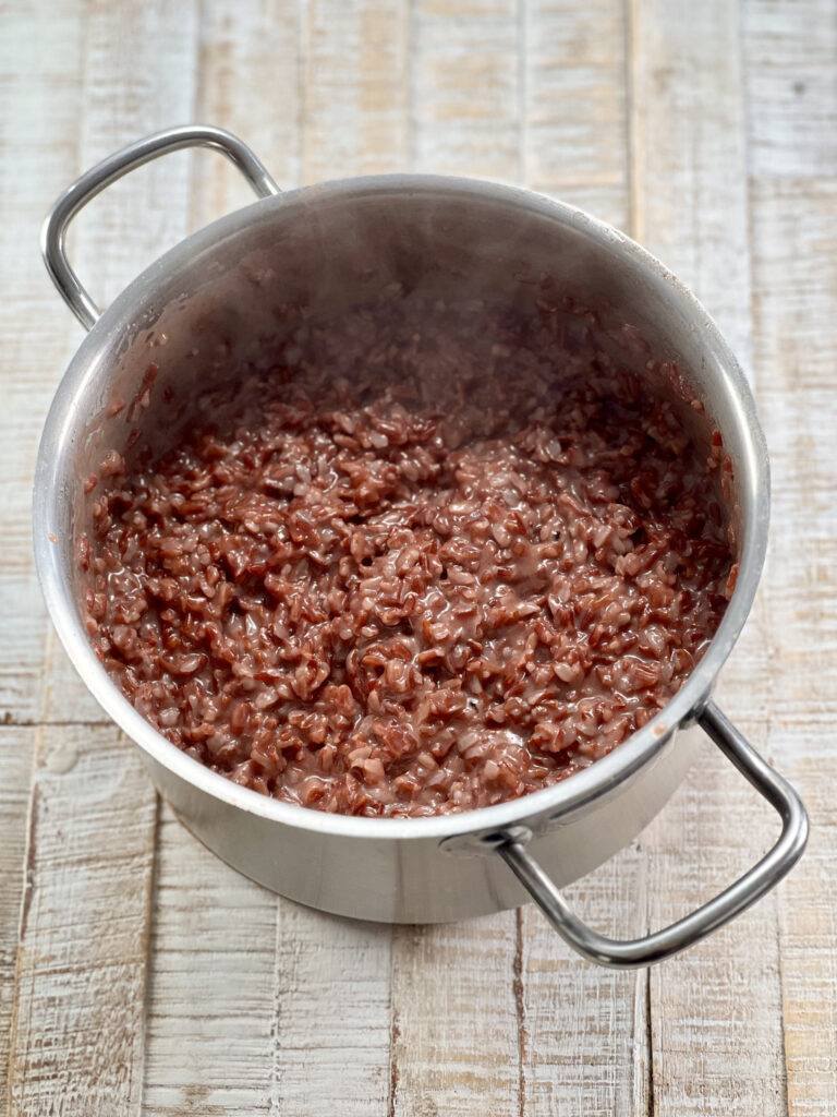 Soft cooked red rice in a stainless steel pot