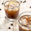 Close up of two espresso sodas in glasses, with coffee beans tossed around them