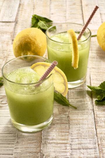 Two glasses of beautifully garnished green mint lemonade