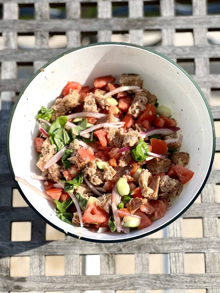 A big white ceramic bowl filled with colorful Panzanella Salad