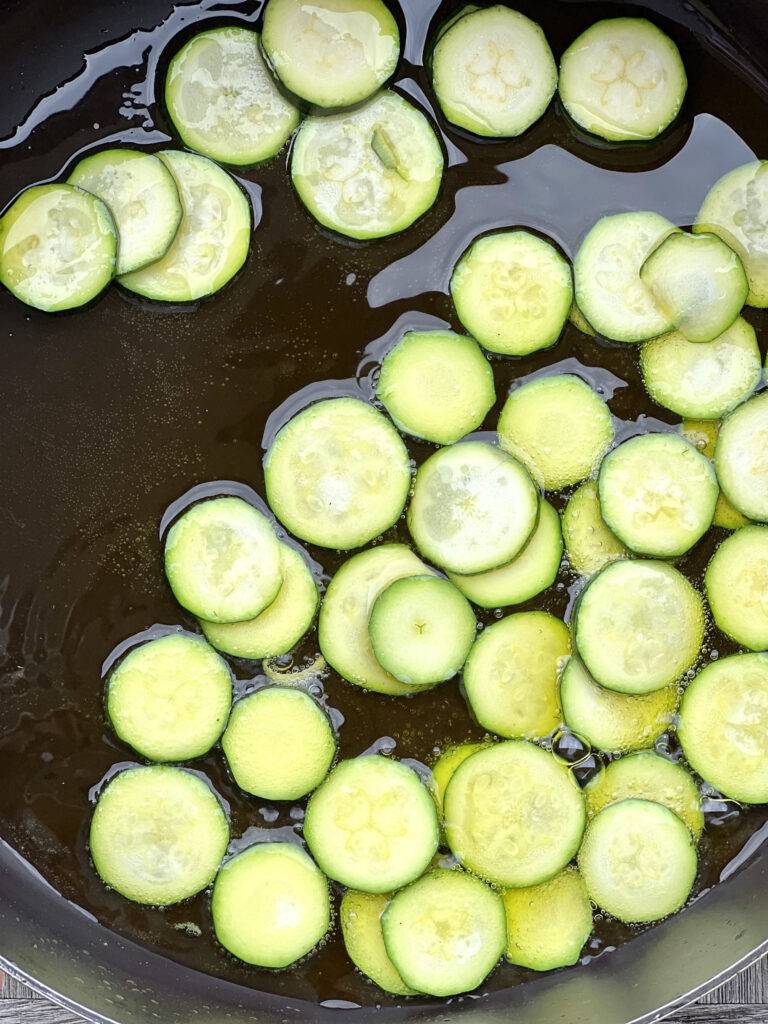 Zucchini slices together with olive oil in a pan