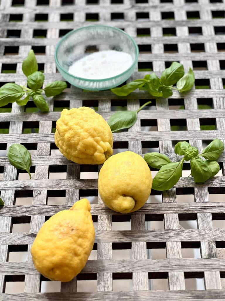 Three Amalfi lemons, fresh basil and sugar on a wooden table