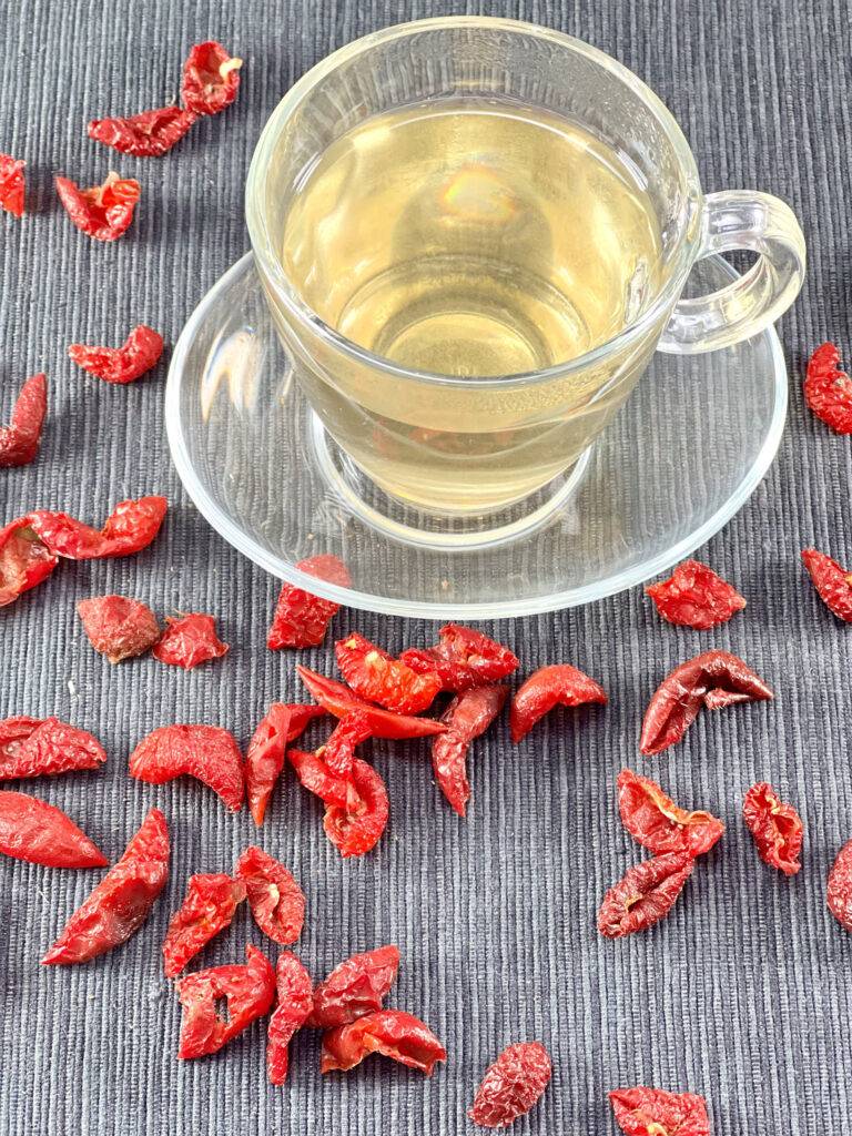 A cup of rose hip tea with rose hips around them