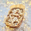 Beautifully garnished vegan shortbread cookies in a wooden bowl with fairy lights around them