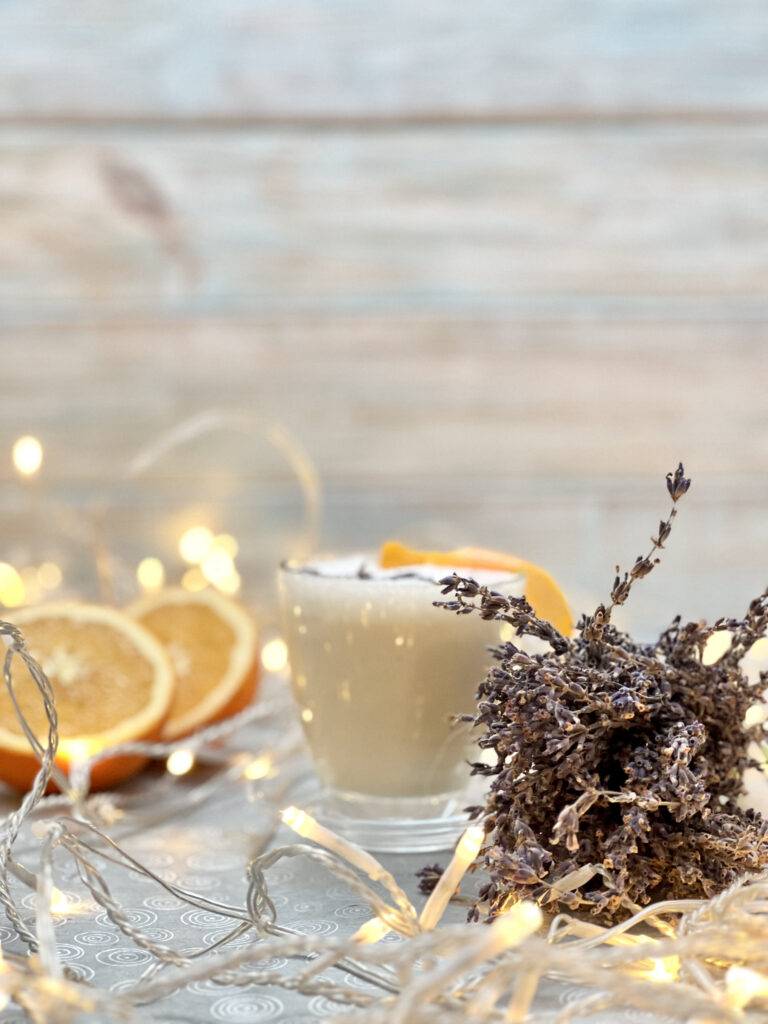 A cup with lavender infusion, dried lavender, orange, and christmas fairy lights