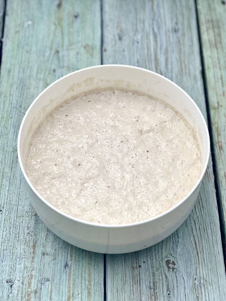 Risen yeast dough for vegan banana pancakes in a white bowl