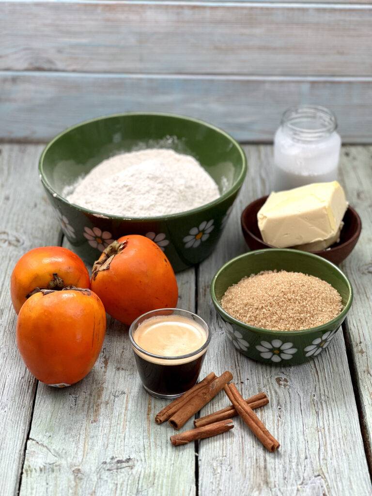 Ingredients for vegan persimmon tarts (flour, vegan whipped cream, persimmons, espresso, cinnamon, espresso, vegan butter substitute) in green bowls