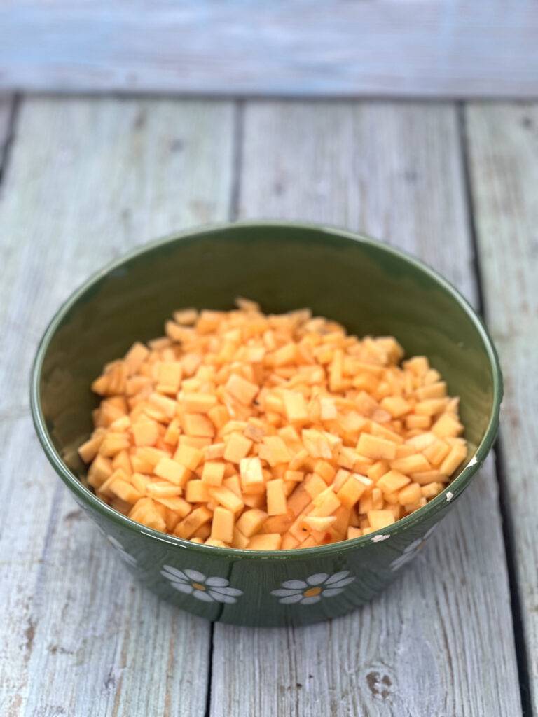 A green ceramic bowl filled with finely diced ripe persimmon cubes