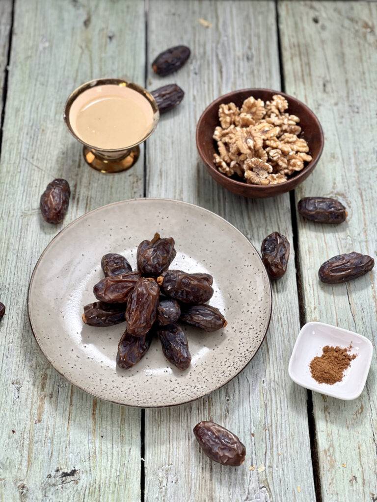 Ingredients for tahini stuffed dates in little bowls on a wooden underground