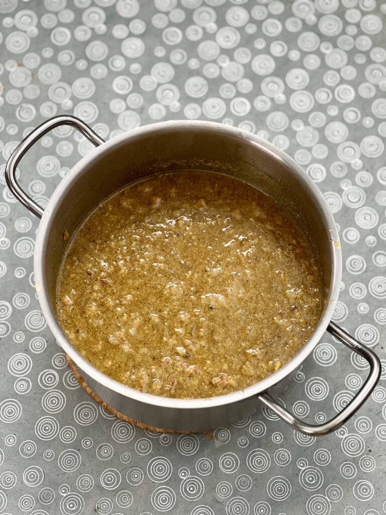 Simmering vegan fesenjan topped with liquid