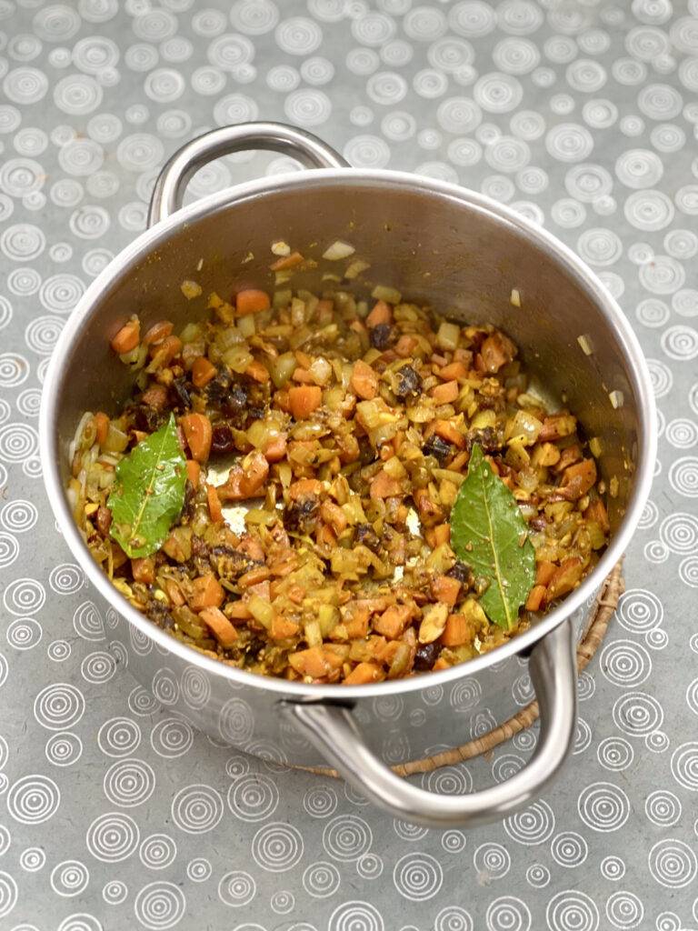 Vegetables, rice and spices sautéing in a stainless steel pot