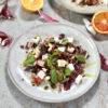 A plate of radicchio salad, beautifully garnished with feta cheese, basil and pumpkin seed oil.