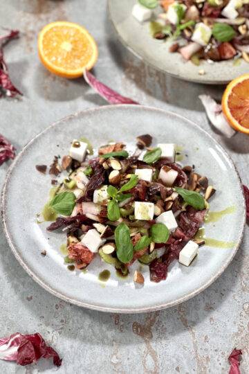 A plate of radicchio salad, beautifully garnished with feta cheese, basil and pumpkin seed oil.
