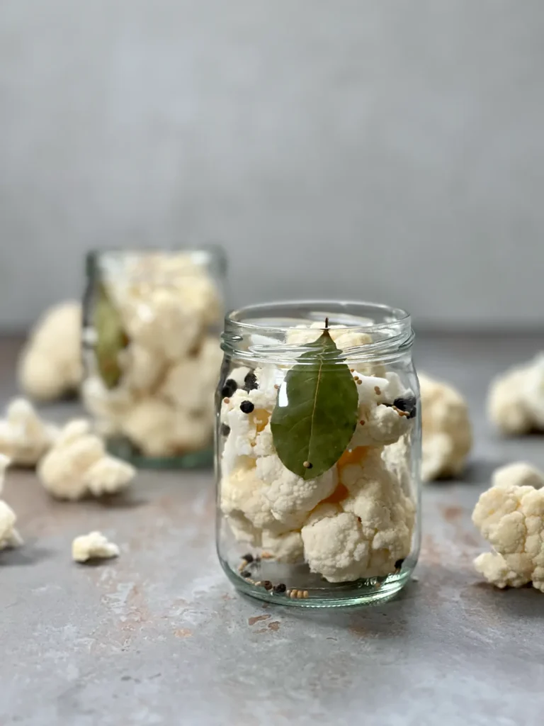 Cauliflower florets and pickling spices packed in glass jars