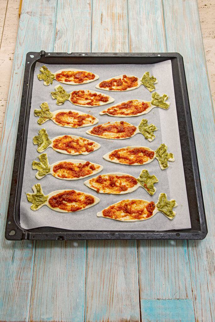 Puff Pastry Carrots are prepared with green and red pesto, placed on baking paper on the baking tray.