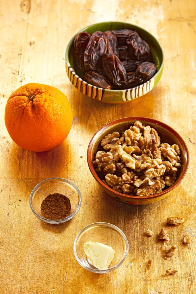 The ingredients for Date cookie filling in bowls, dates, walnuts, cinnamon, vegan butter and an organic orange.