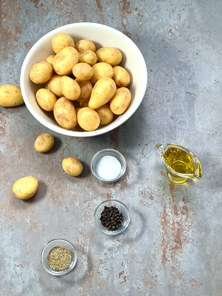 Small young potatoes (Drillinge), Salt, Pepper and Dried Rosemary in ceramic bowls
