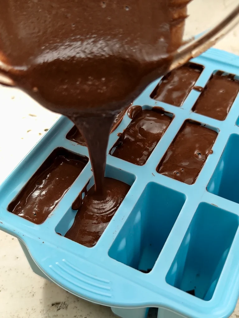 The freshly blended chocolate mixture is poured into the popsicle mold.