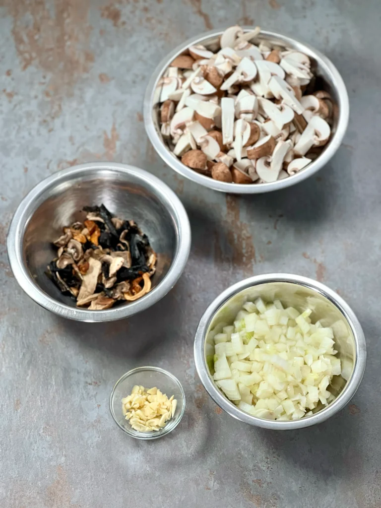 Ingredients for mushroom risotto prepared (sliced and soaked mushrooms, diced onions, minced garlic)