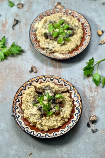 A bird's eye angle of two served plates of creamy vegan mushroom risotto w