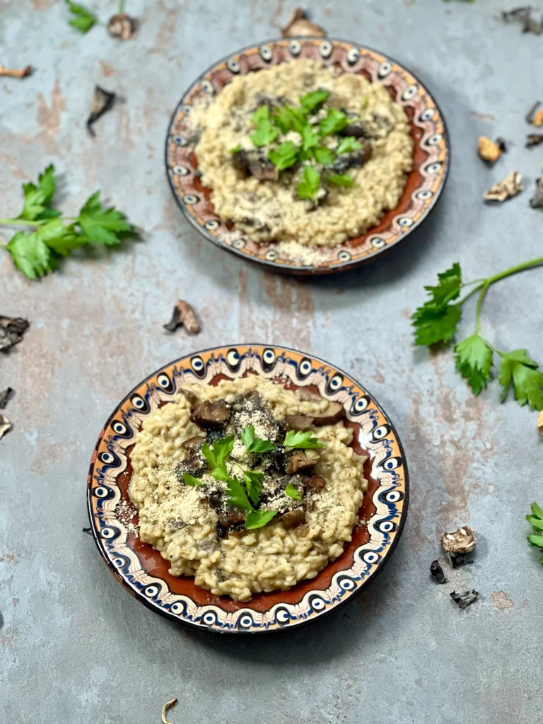 A bird's eye angle of two served plates of creamy vegan mushroom risotto w