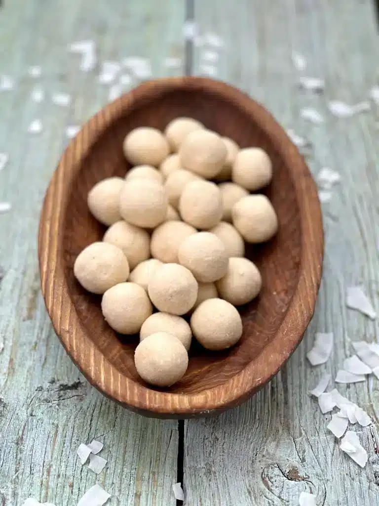 Beautifully smooth rolled coconut truffles in a wooden bowl