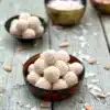 Two bowls of Vegan Coconut Truffles with coconut flakes and almonds as garnishes