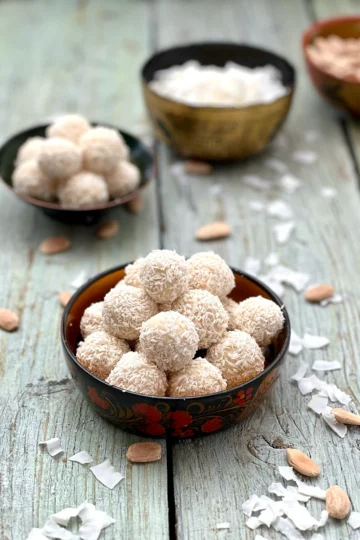 Two bowls of Vegan Coconut Truffles with coconut flakes and almonds as garnishes