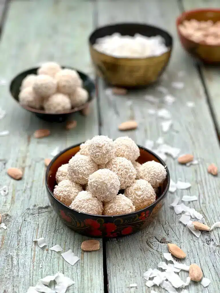 Two bowls of Vegan Coconut Truffles with coconut flakes and almonds as garnishes