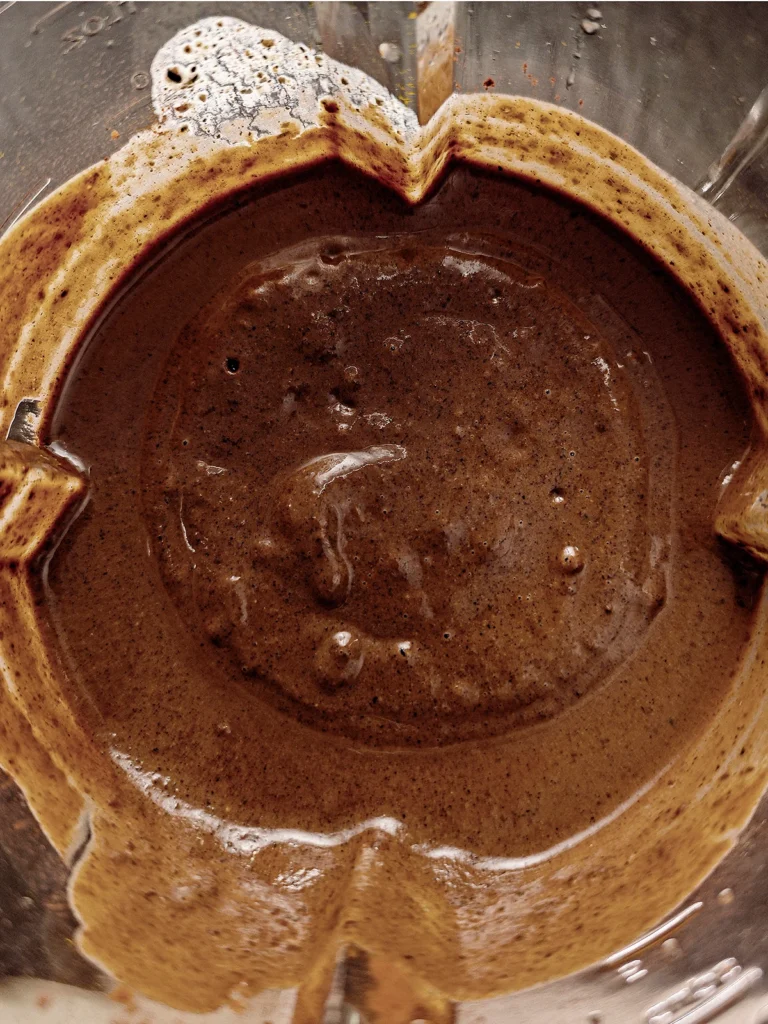 A close-up view of the blender jar. You can see the brown pureed mixture for the Halloween popsicles with sesame.