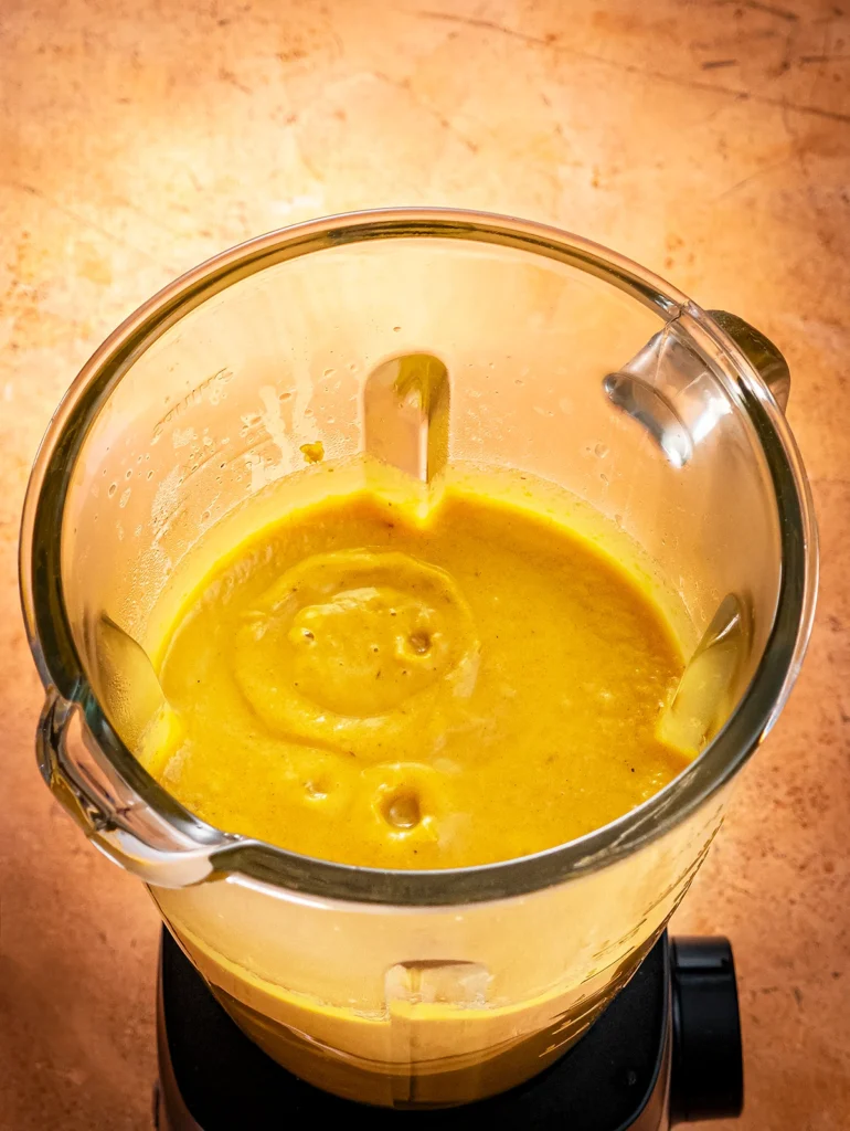 A close-up view of the blender jar. You can see the orange pureed mixture for the Halloween popsicles with pumpkin.