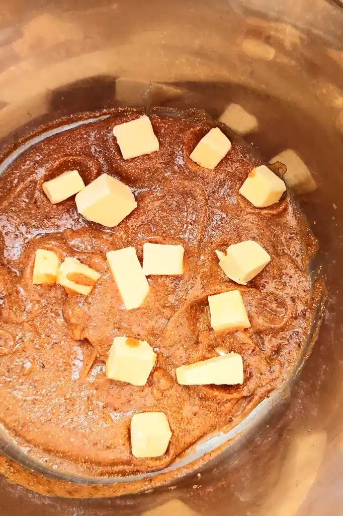 In a large stainless steel bowl is the mixture for the yeast dough - with dates, coconut milk, yeast and pieces of butter substitute.