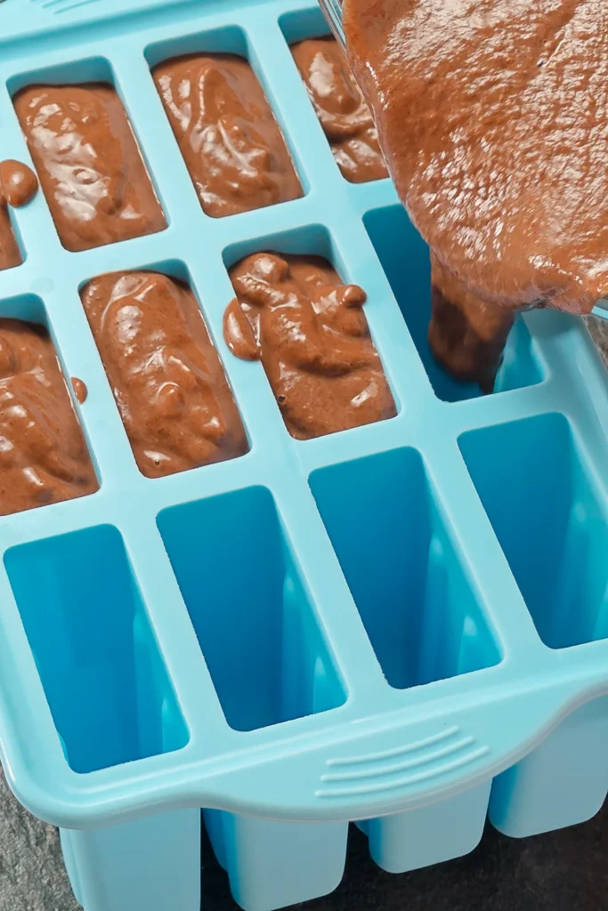 Filling the popsicles mold with the ready mixed brown Halloween sesame mixture.