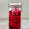 A big mason jar of Pickled Turnips on a dark stone surface