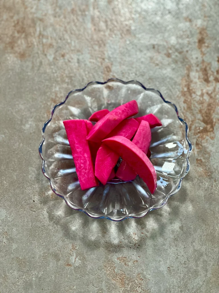 A few slices of pickled turnip on a beautiful crystal glass plate