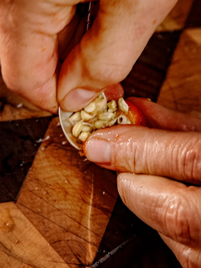 Two hands remove the seeds from a rosehip fruit.