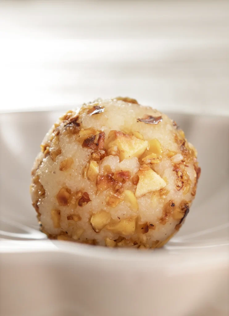 A close-up of a semolina dumpling with roasted hazelnuts in a white bowl.