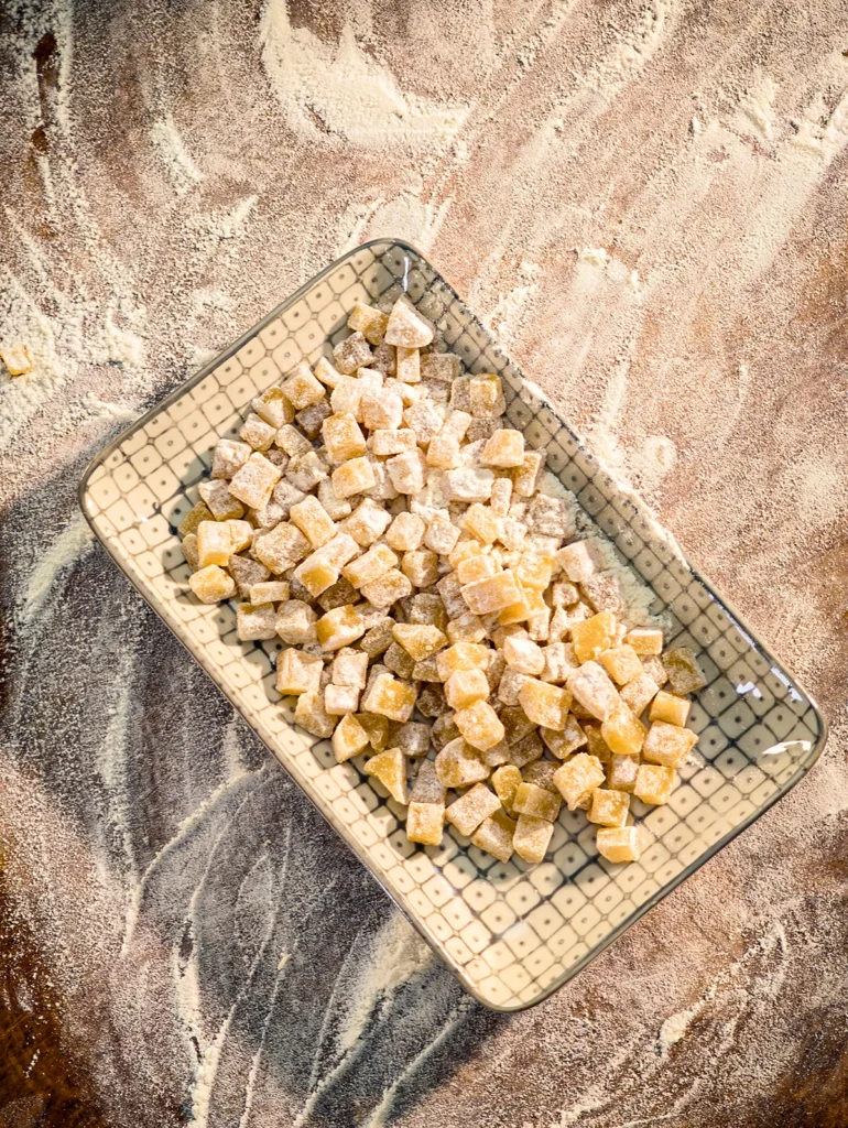 On a large floured wooden kitchen board is a shallow bowl with chopped small pieces of marzipan, also floured.