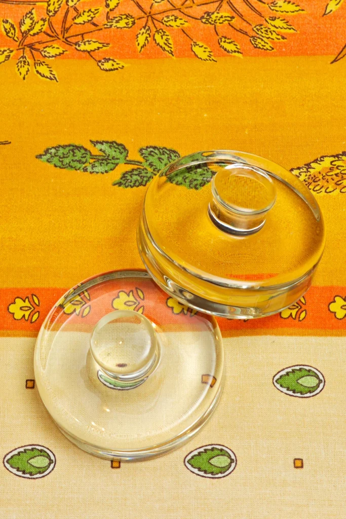 Two ferment weights on a patterned orange and yellow tablecloth.