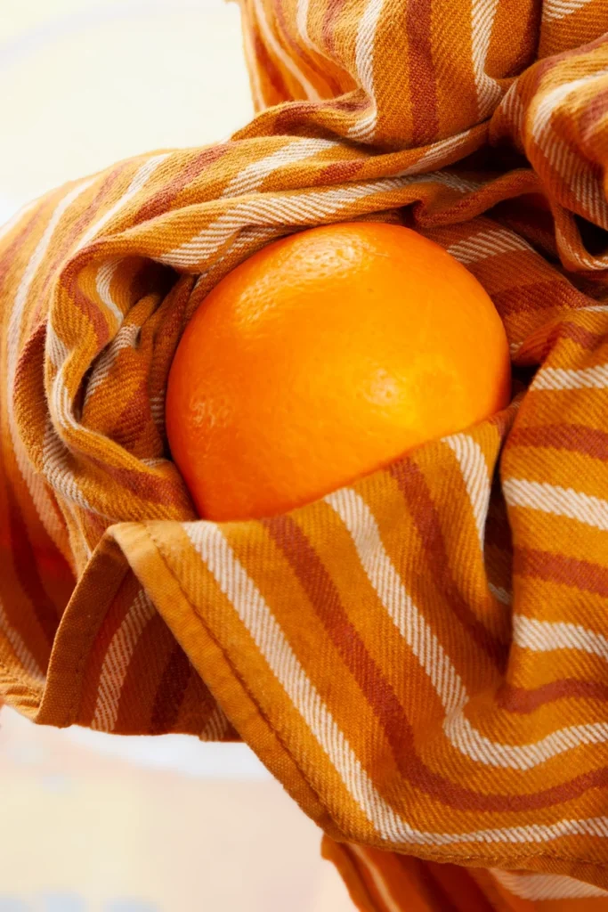 The orange is dried by a kitchen towel.