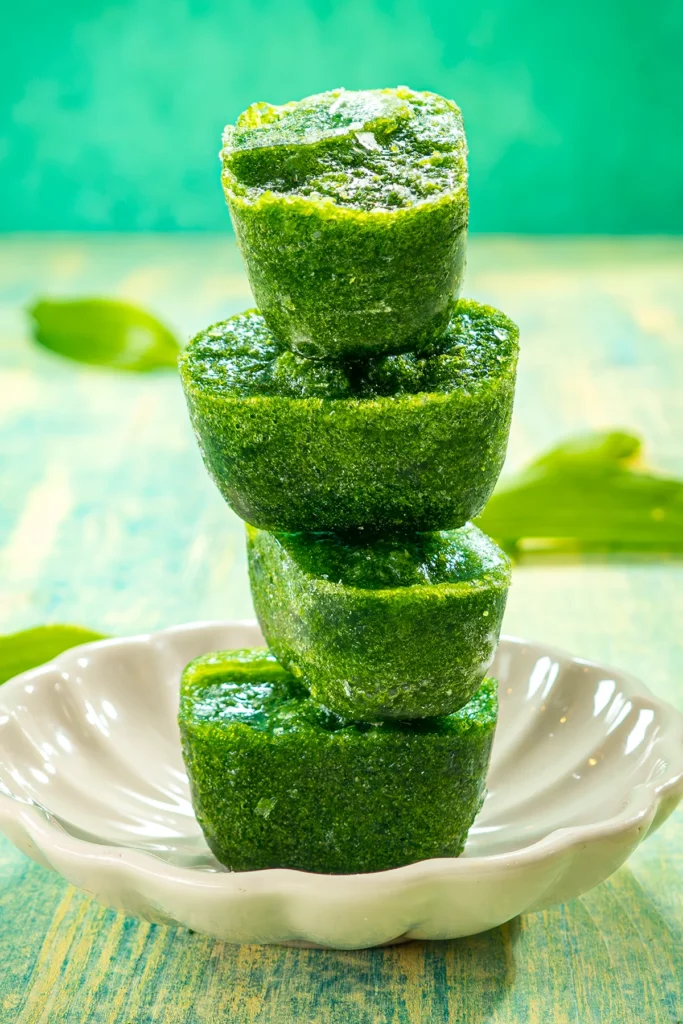 Four ice cubes made from wild garlic puree are stacked on top of each other in a flat white bowl.