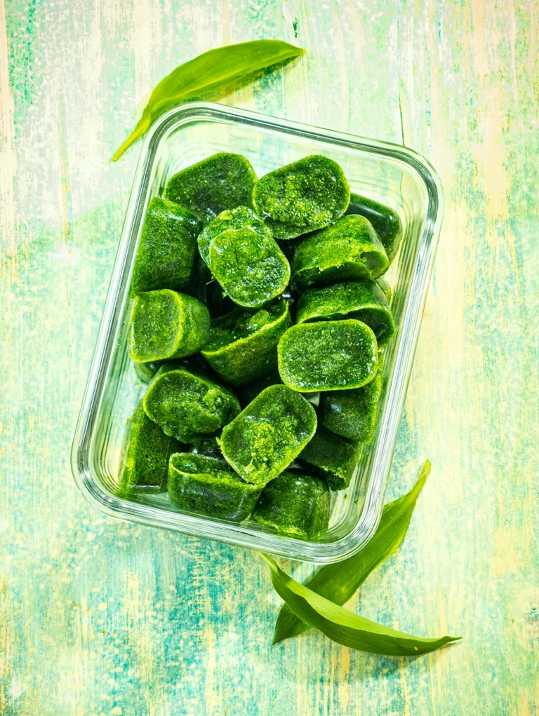 A glass bowl filled with ice cubes made from wild garlic puree.