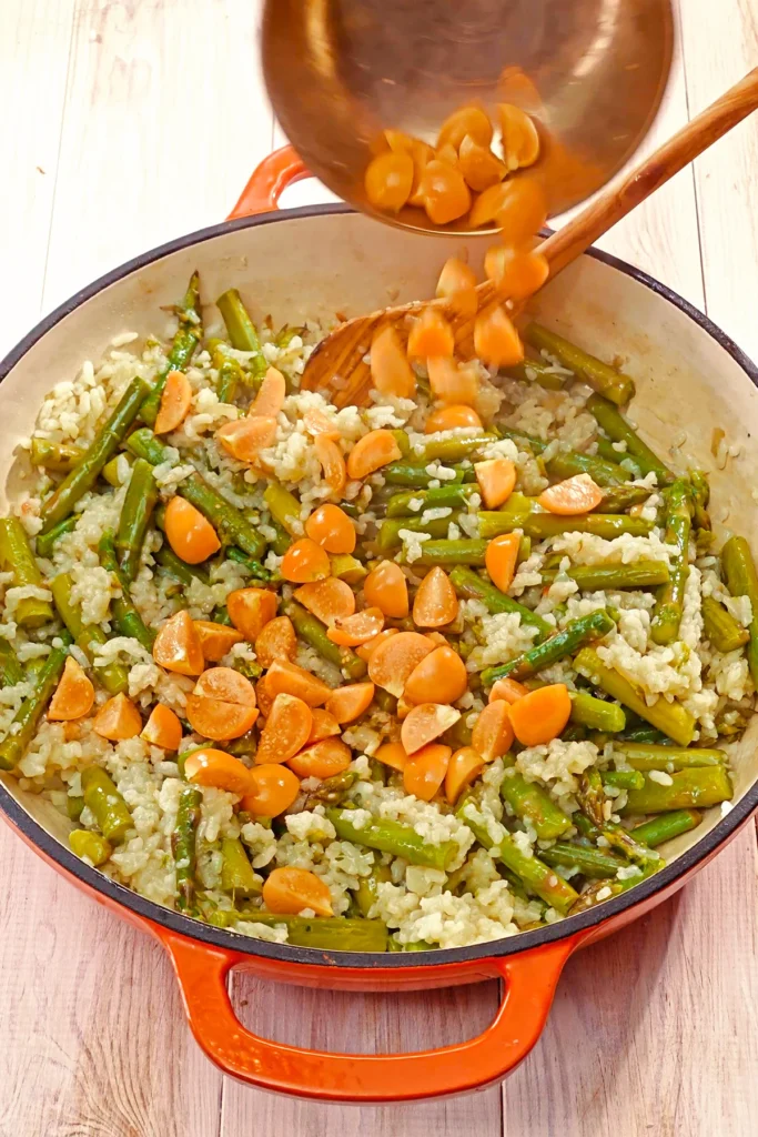 The quartered physalis are added to the pan with the asparagus risotto.