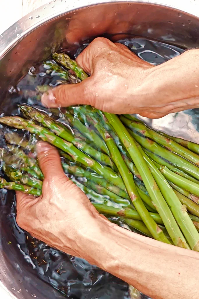 The fresh green asparagus is washed in a bowl.